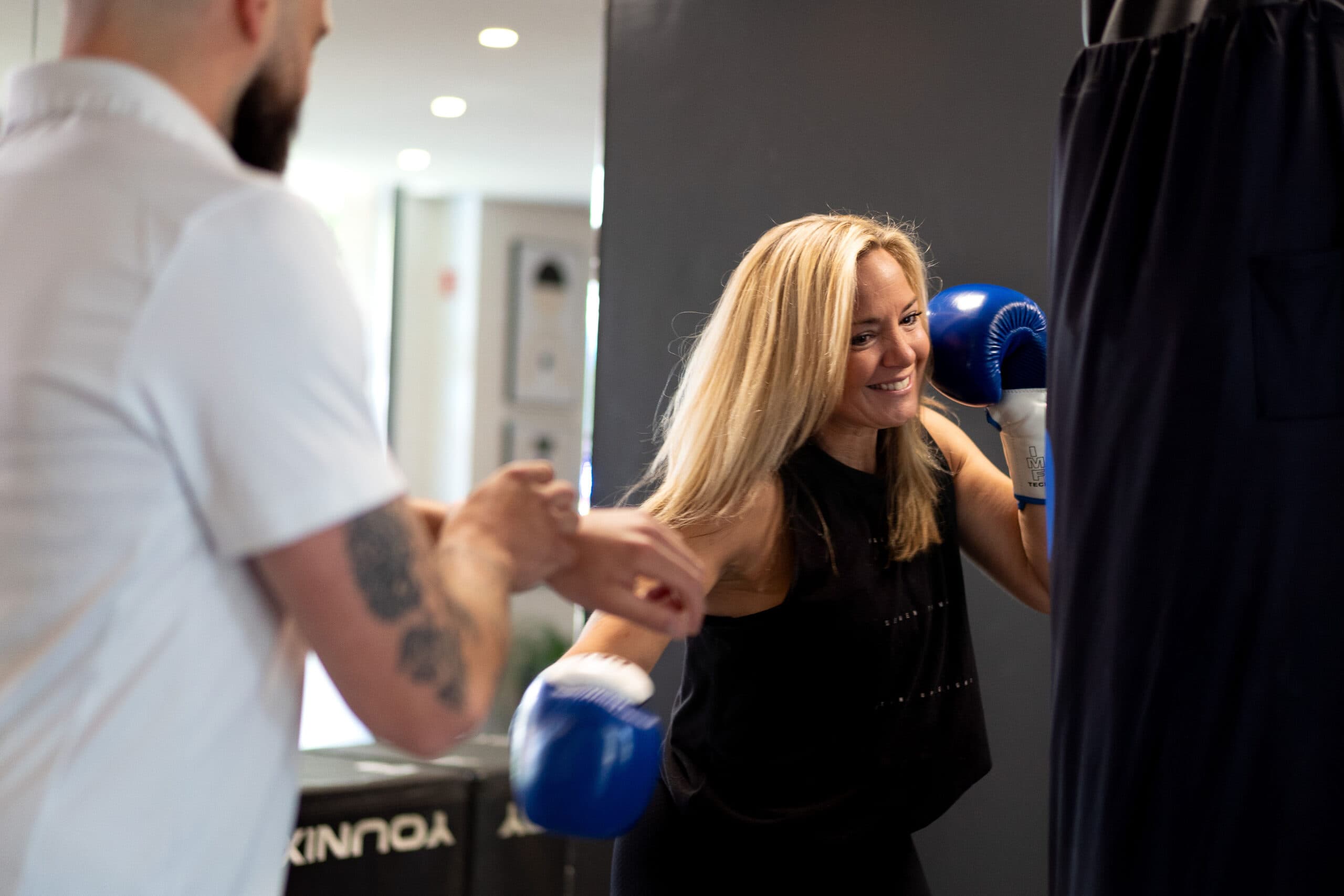 Une cliente s’entraîne aux gants de boxe avec son coach dans un studio My Coach by Ginkgo